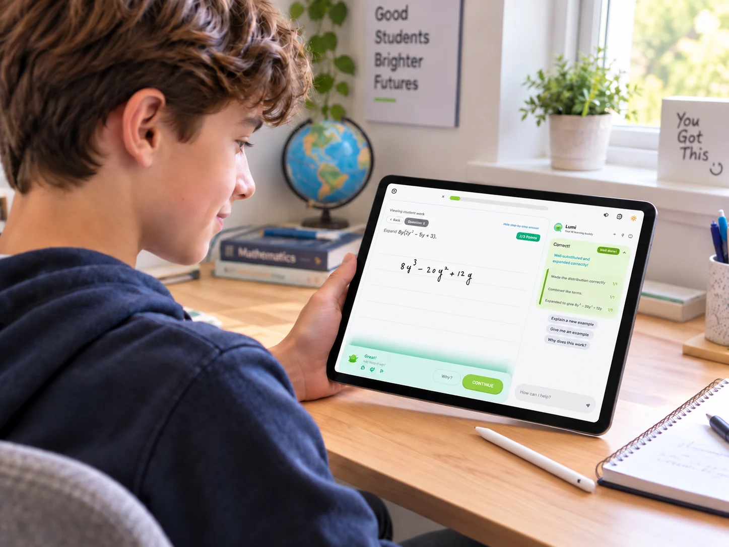 A student at a desk holding an iPad showing Ilmino practice mode: a handwritten answer marked 2 out of 2, with Lumi explaining each mark